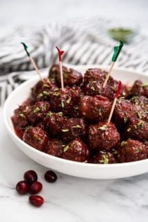 A bowl of meatballs with sticky sauce and toothpicks on a few of them