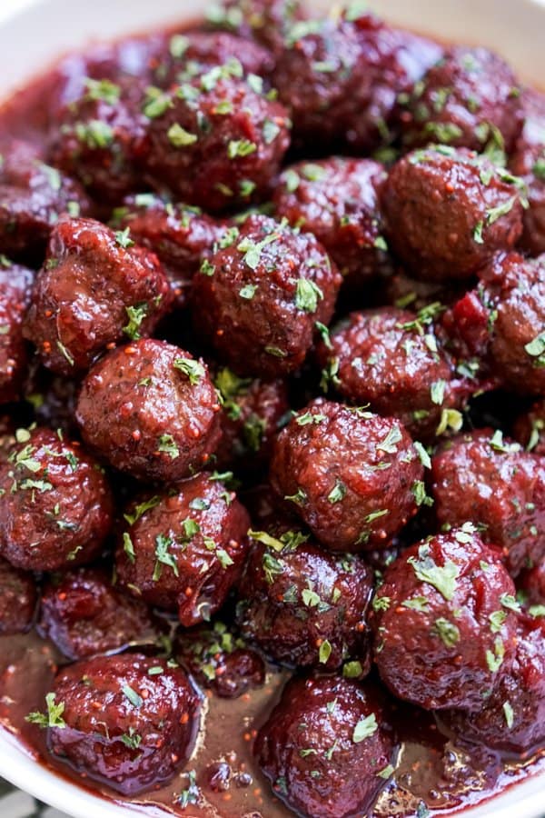 Closeup on a lots of meatballs coated with sticky cranberry sauce