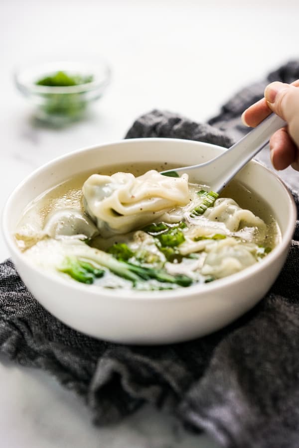 PIcking up a wonton from a bowl of wonton soup