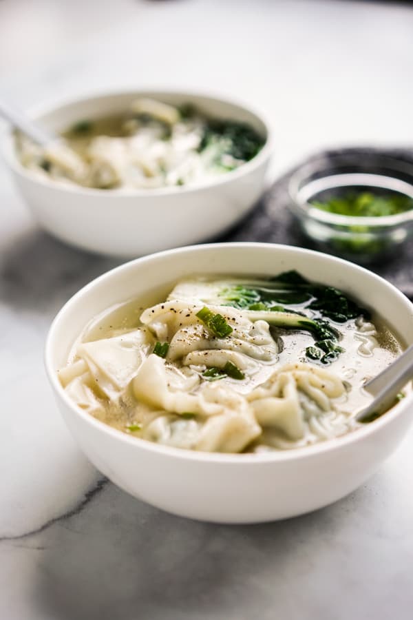 A bowl of wonton soup with another one in the background