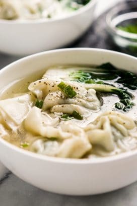 A bowl of soup with wontons and bak choy