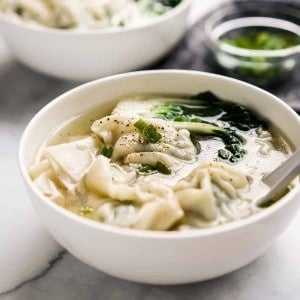 A bowl of soup with wontons and bak choy