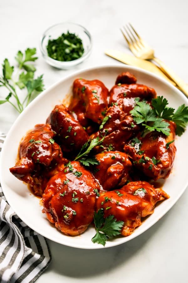 A plate of chicken thighs coated in sticky bbq sauce