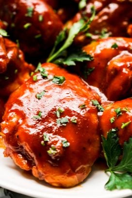 Close up of a piece of bbq chicken thigh coated with thick bbq sauce