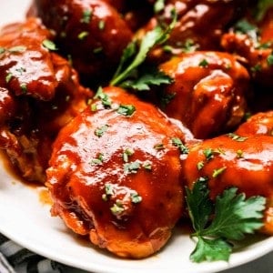 Close up of a piece of bbq chicken thigh coated with thick bbq sauce