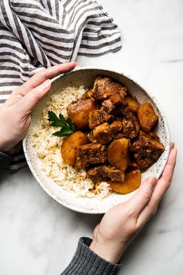 Hand holding a bowl of Chinese Braised Pork Belly