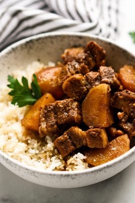 A bowl of pork belly and potatoes in soy sauce on top of rice