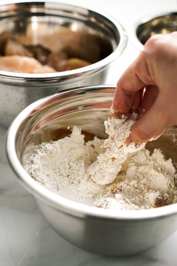 Dipping chicken into flour mixture