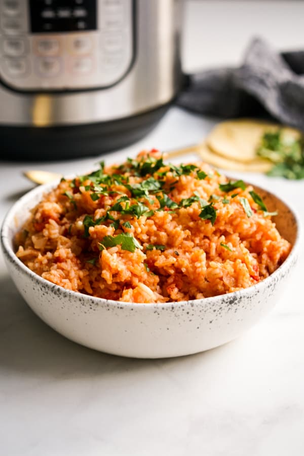 A bowl of Mexican rice with an Instant Pot behind it