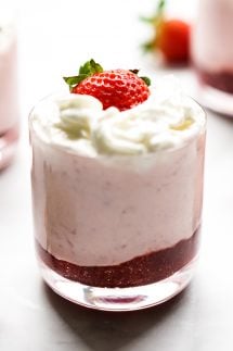 A jar of strawberry mousse with whipped cream and fresh strawberry