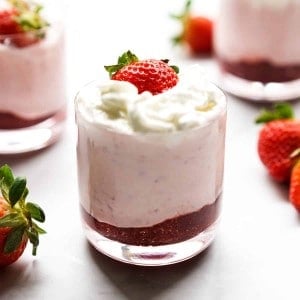 A jar of strawberry mousse with whipped cream and fresh strawberry