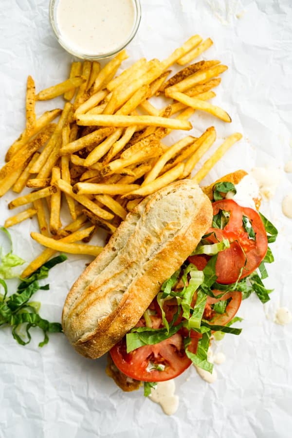 French baguette with fried fish, tomatoes and lettuce, French fries, and remoulade