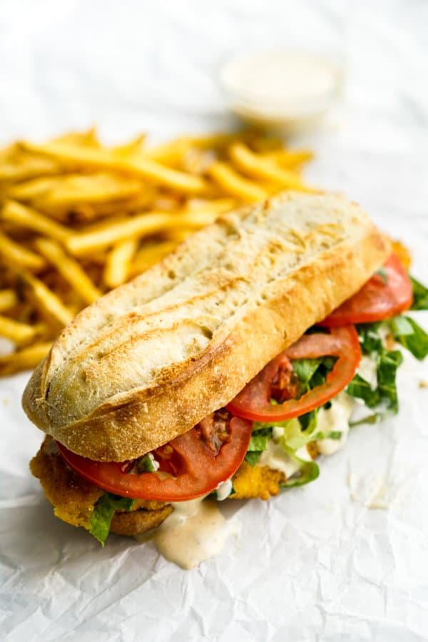 French baguette loaded with fried fish, lettuce, tomatoes, and remoulade