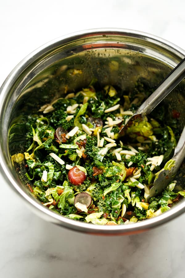 Tossing kale, Brussels Sprouts, Grapes and almonds in a large bowl with vinaigrette