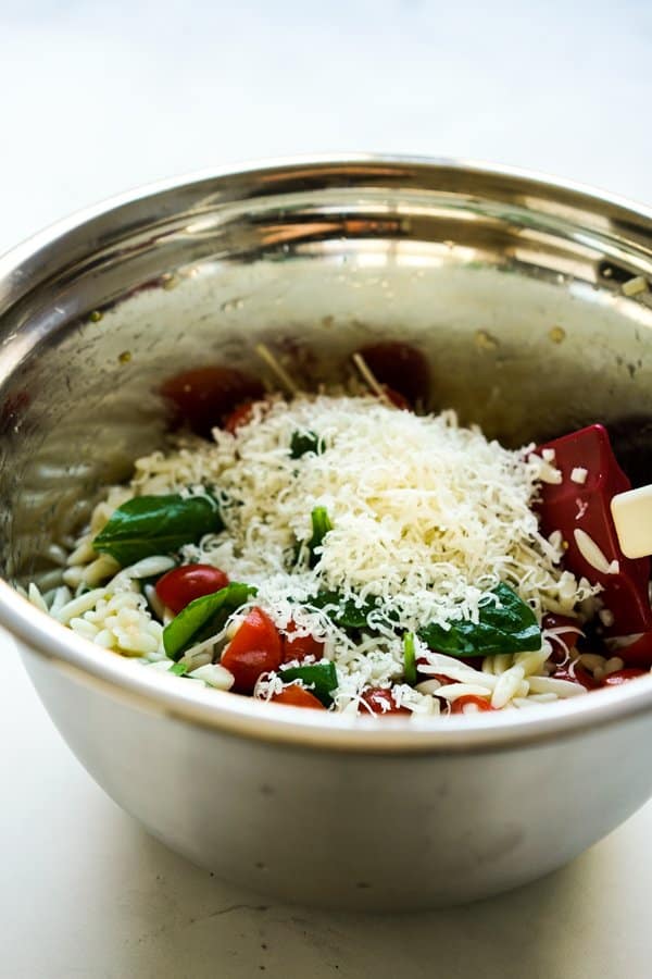 A bowl of orzo salad with grated parmesan cheese on top