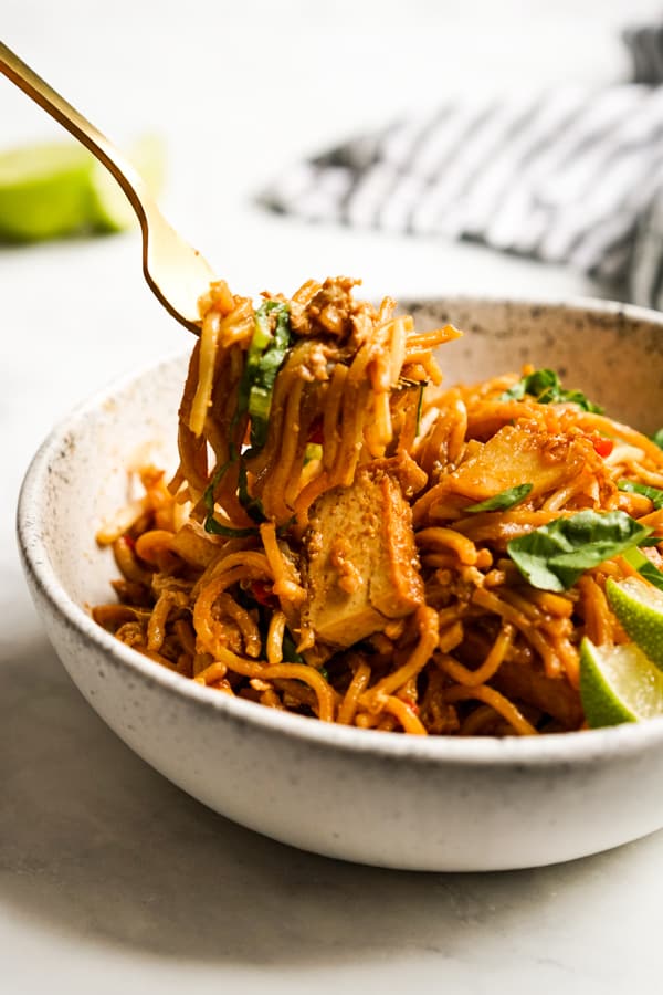 Fork lifting up noodles from a bowl