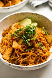 A bowl of Mee Goreng noodles with lettuce and lime garnish