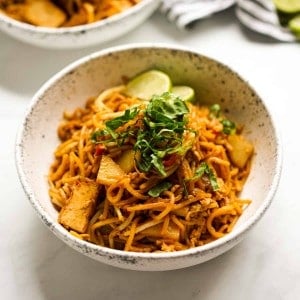 A bowl of Mee Goreng noodles with lettuce and lime garnish