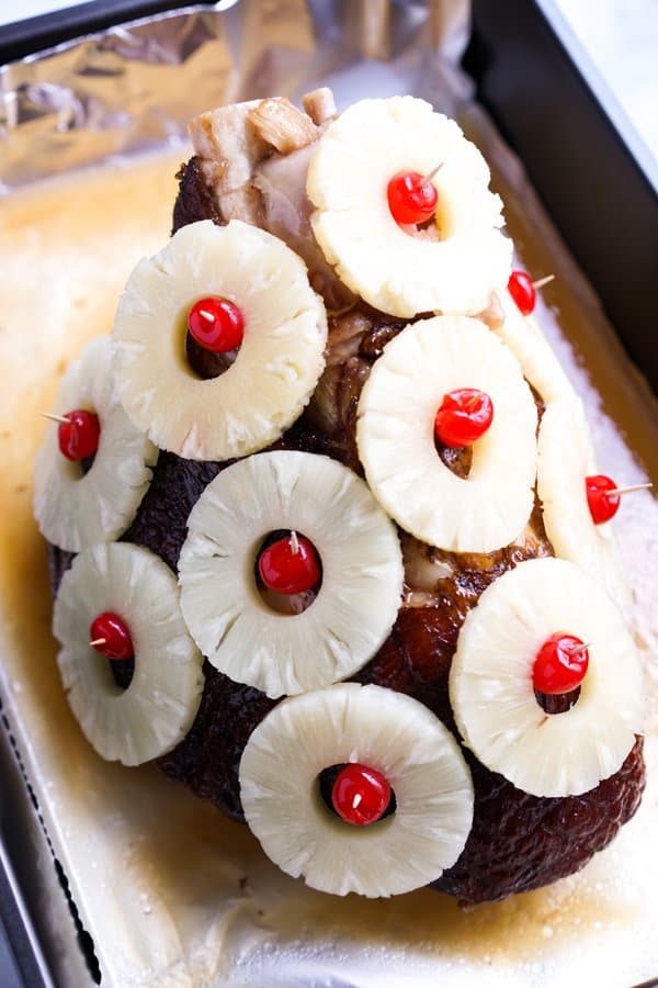 Ham in baking dish with pineapple rings and cherries secured to it