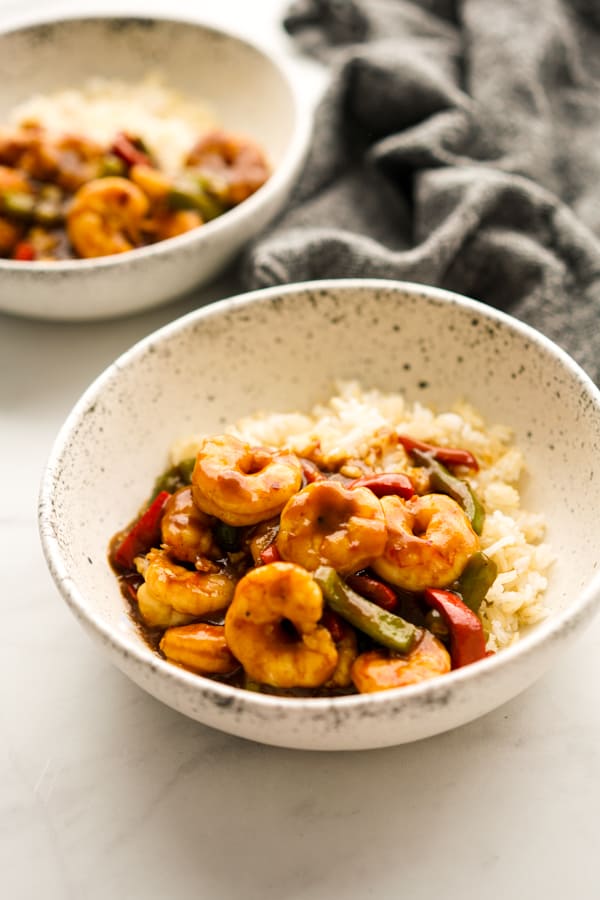 A bowl of rice topped with stir fried shrimp