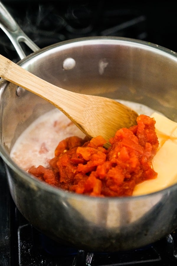 Cooking chicken broth, velveta cheese, tomatoes in a pot