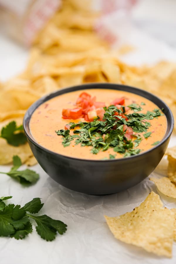 A bowl of queso surrounded by tortilla chips