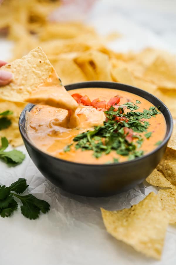 Dipping a tortilla chips into a bowl of queso