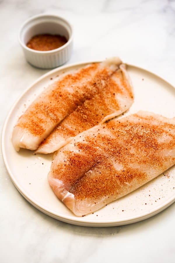 Uncooked tilapia fillets coated in spices