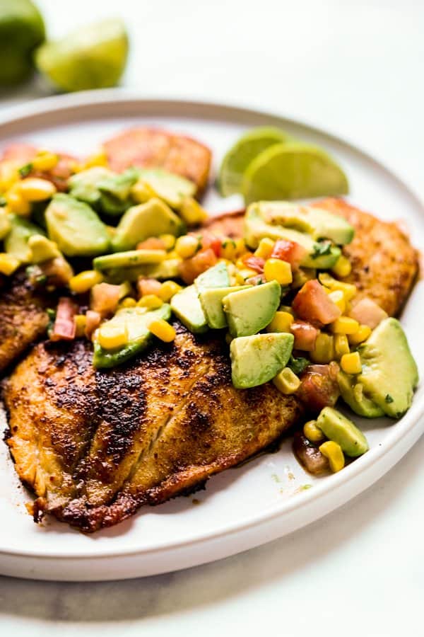 Seared tilapia fish with avocado and corn on top