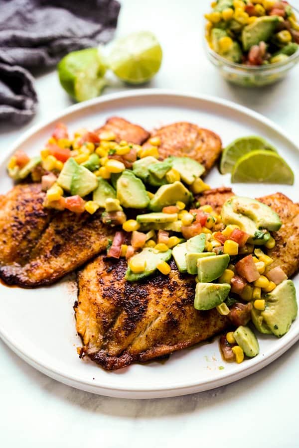 a plate of pan seared tilapia topped with avocado corn salsa