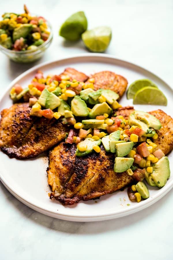 A plate of Tilapia with avocado, tomatoes, and corn salsa