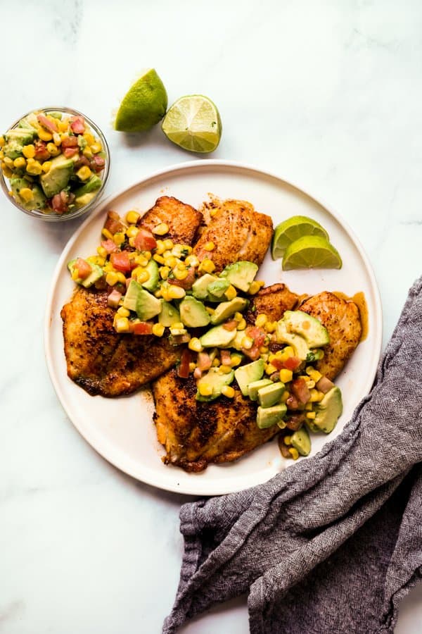 Top down view of fish fillets with avocado, corn and tomatoes