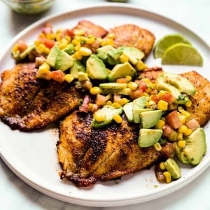 A plate of tilapia with avocado corn salsa