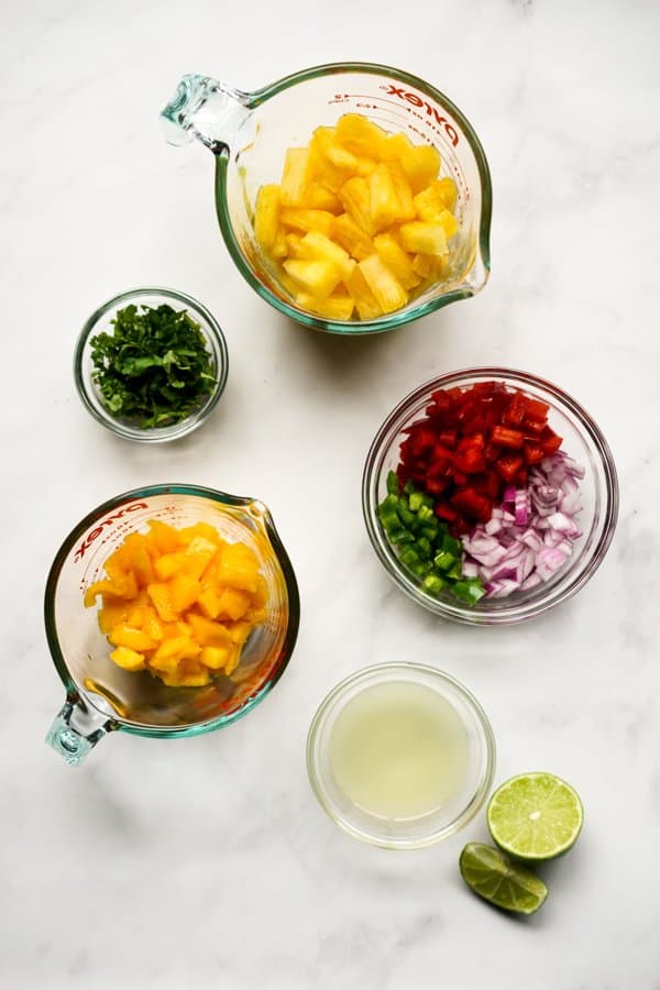 Cubed mangoes, cubed pineapples, cilantro, red bell pepper, red onions, jalapeño, and lime juice