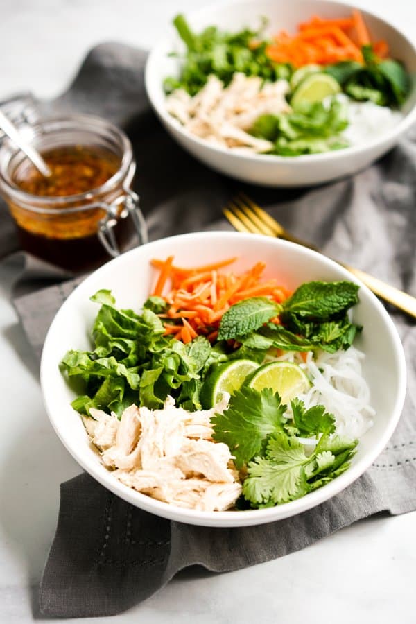 Two bowls of Vietnamese Noodle Salad with a jar of sauce in the background