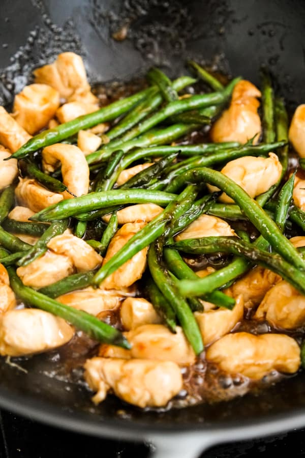 Stir frying chicken and green beans in skillet