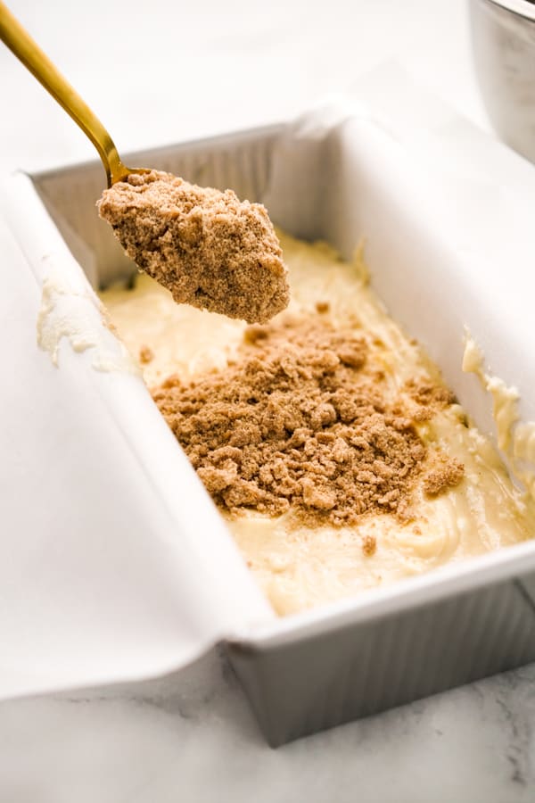 Adding crumble to apple bread mixture in a bread pan