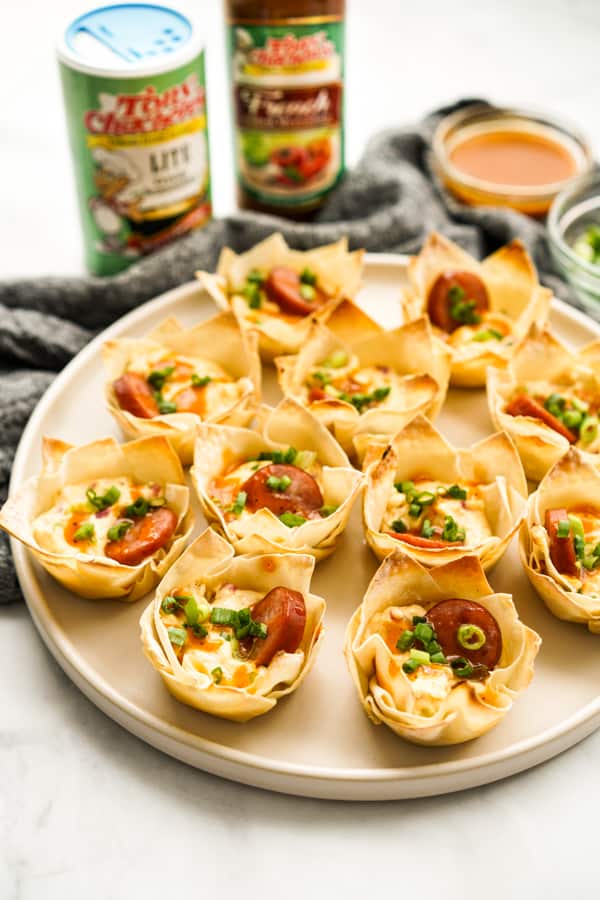 A plate of wonton cups with seasoning and sauces in the background