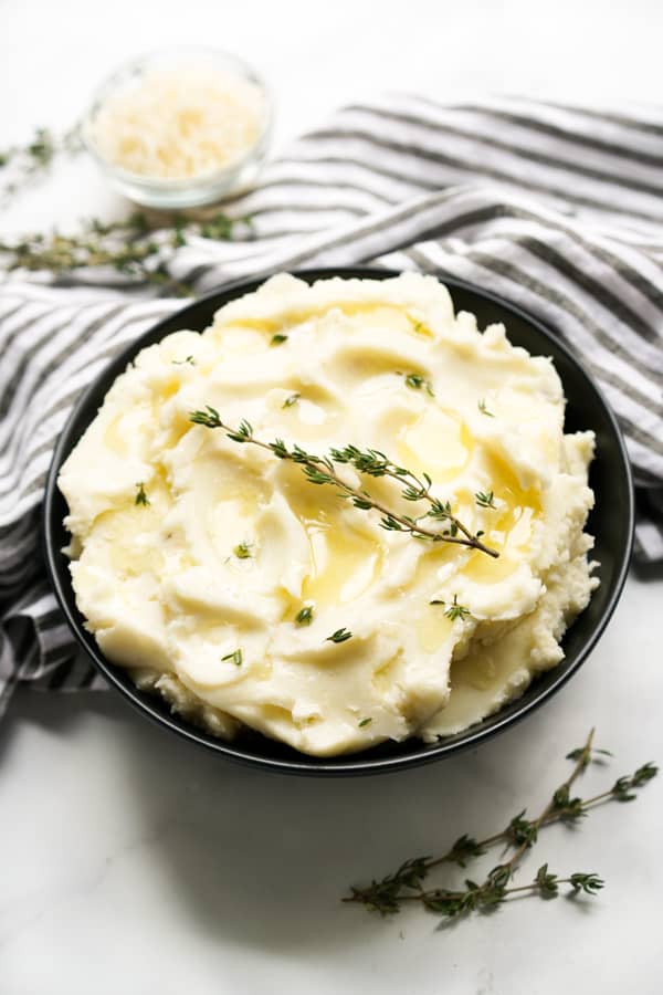 A bowl of mascarpone mashed potatoes topped with fresh thyme