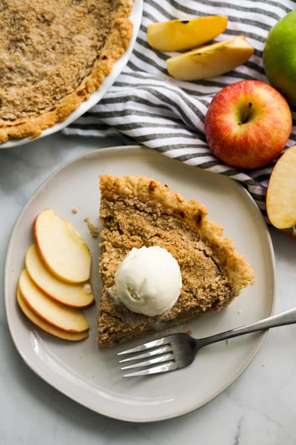 Top down view of a slice of apple pie with crumb topping and ice cream