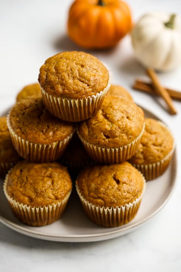 Muffins on a plate with pumpkins and cinnamon sticks in the background