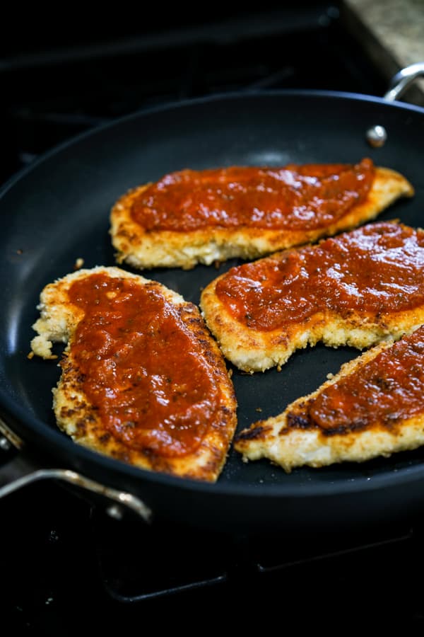 Chicken parmesan on a skillet topped with marinara sauce