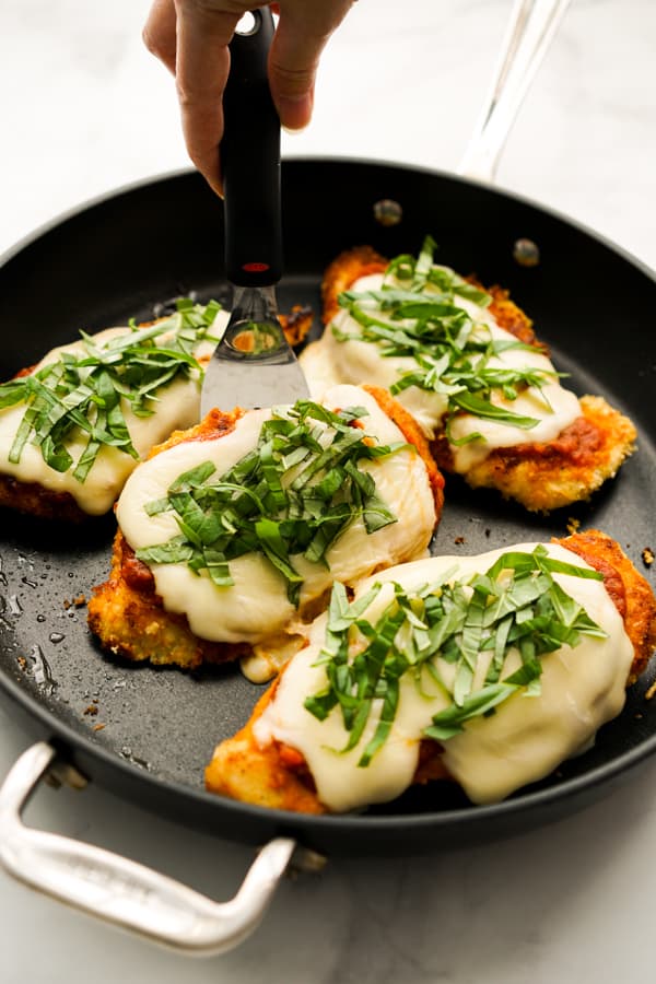 Lifting up a piece of Skillet Chicken Parmesan