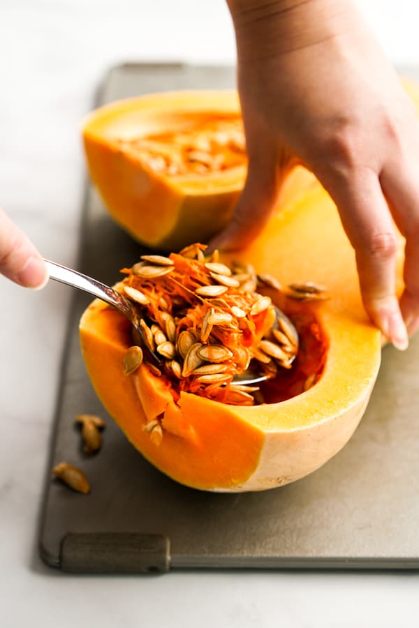 Digging out seeds from whole butternut squash