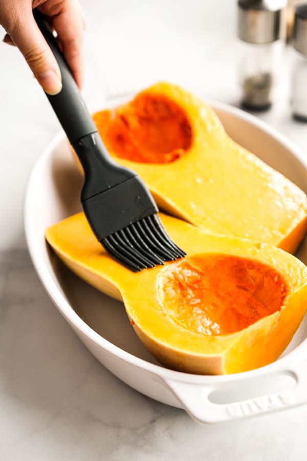 brushing olive oil on the surface of butternut squash