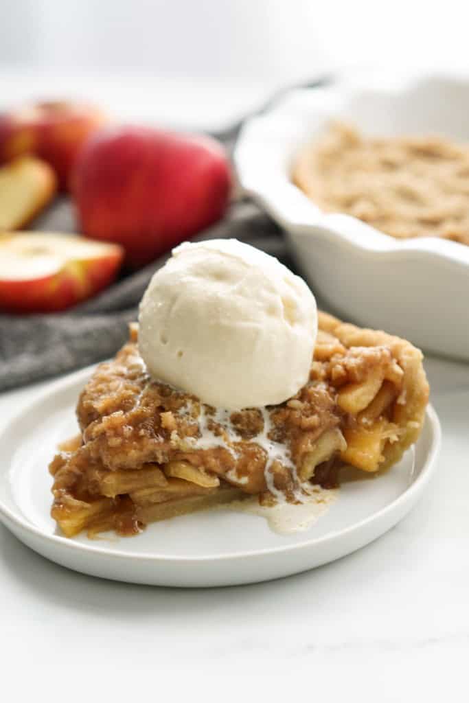 A sliced of apple crumble pie topped with vanilla ice cream