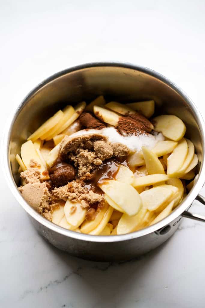Sliced apple in a pot topped with brown sugar and spices