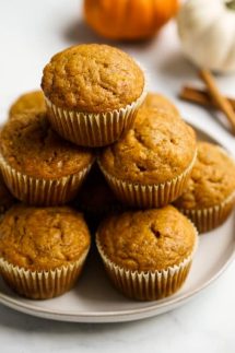 Muffins on a plate with pumpkins and cinnamon sticks in the background