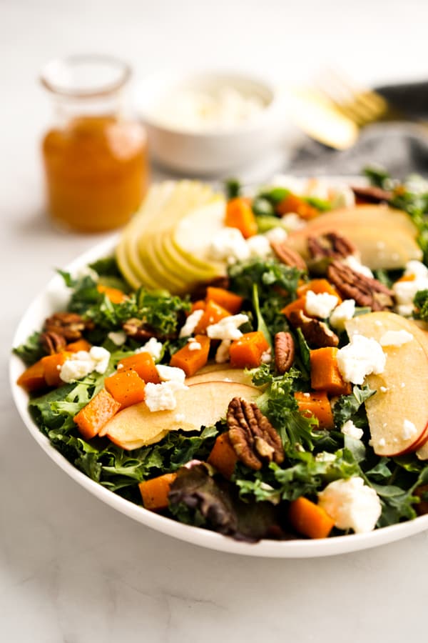 A plate of Fall Harvest Salad with dressing in the background