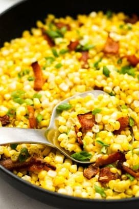 Scooping out pan fried corn kernels and bacon